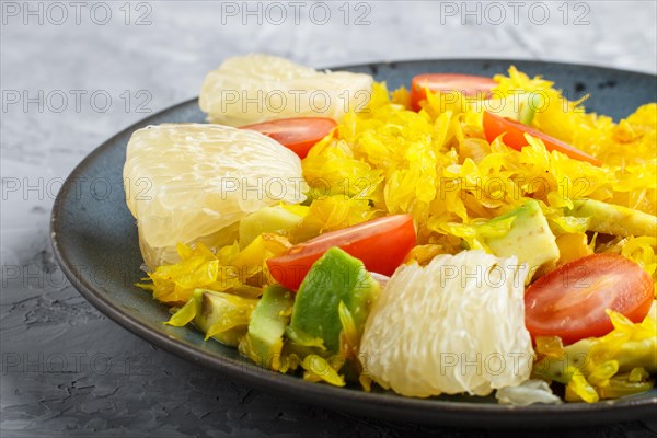 Fried pomelo with tomatoes and avocado on gray concrete background. side view, close up, myanmar