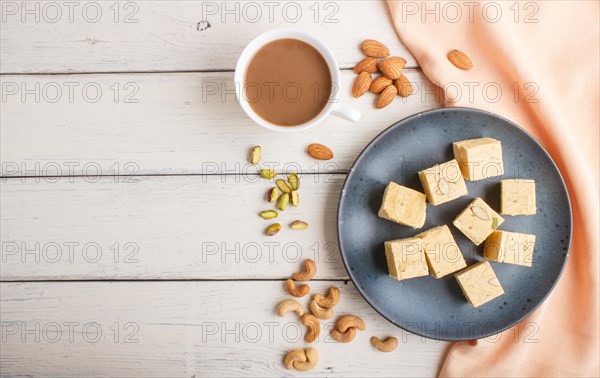 Traditional indian candy soan papdi in a blue ceramic plate with almond, pistache, cashew and a cup