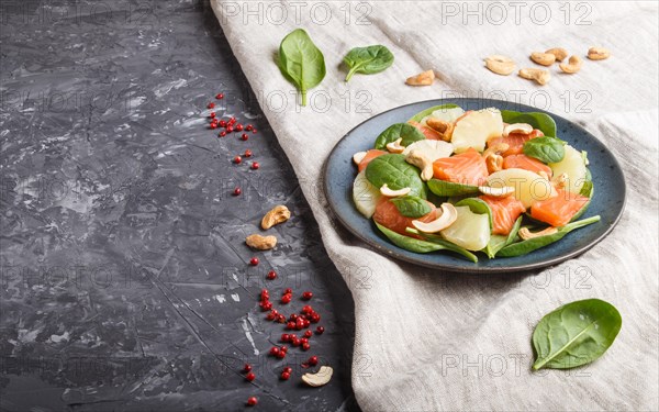 Fresh salmon with pineapple, spinach and cashew on a black concrete background. Side view, copy