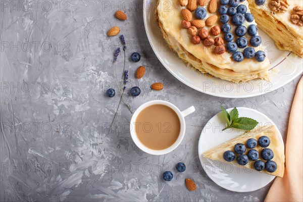 Homemade layered Napoleon cake with milk cream. Decorated with blueberry, almonds, walnuts,