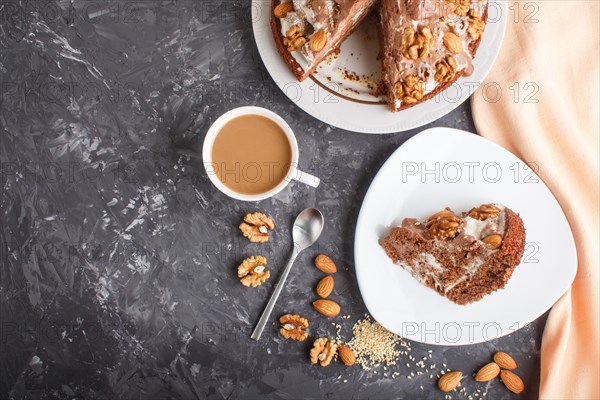 Homemade cake with milk cream, cocoa, almond, hazelnut on a black concrete background with orange