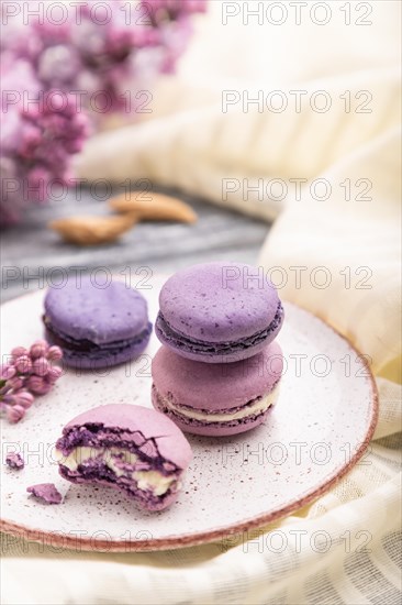 Purple macarons or macaroons cakes with cup of coffee on a gray wooden background and white linen