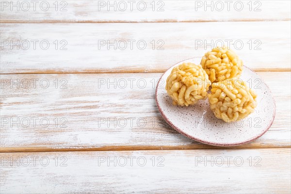 Traditional Tatar candy chak-chak made of dough and honey on a white wooden background. Side view,