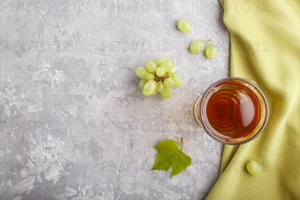 Glass of green grape juice with green textile on a gray concrete background. Morninig, spring,