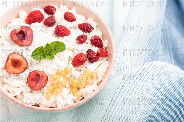 Rice flakes porridge with milk and strawberry in ceramic bowl on white concrete background and blue