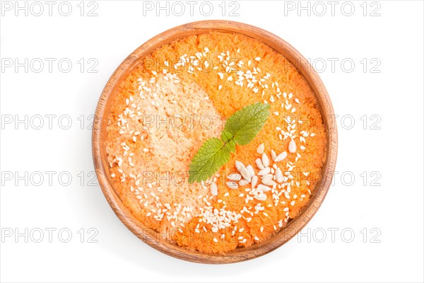 Carrot cream soup with sesame seeds in wooden bowl isolated on white background. top view, flat