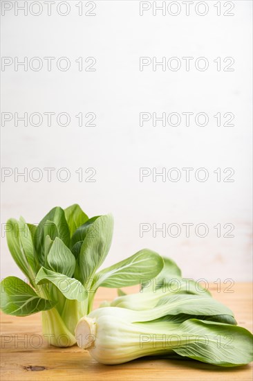 Fresh green bok choy or pac choi chinese cabbage on a brown wooden background. Side view, copy