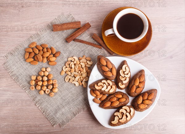 Small cakes potatoes with almonds and cashew nuts on a dessert plate. A cup of coffee, cinnamon,