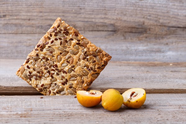 Biscuits with flax, sesame and sunflower seeds and yellow quince fruit on a rustic wooden