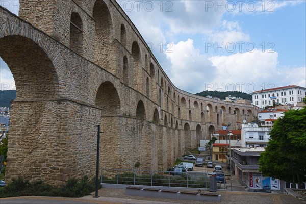 A Roman aqueduct spans a modern cityscape under a cloudy sky, Kavala, Dimos Kavalas, Eastern