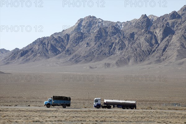 An old round-hood Mercedes truck in front of a new Mercedes truck on a motorway in the central
