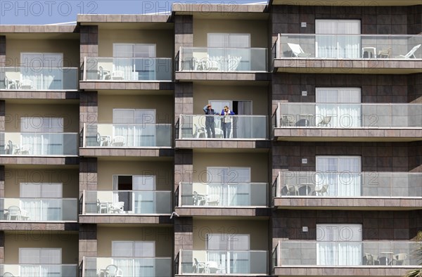 An elderly couple looks out from a balcony of an apartment complex in Torremolinos, Costa del Sol,