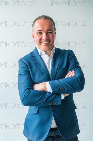 Vertical three quarter length studio portrait of a confident businessman standing proud with arms