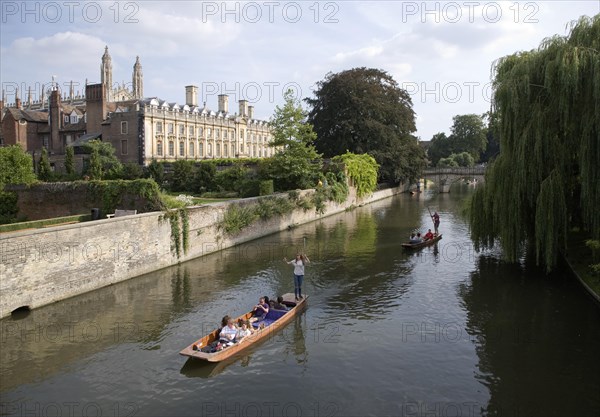People punting in small boats on the River Cam, Cambridge England with Clare College in the