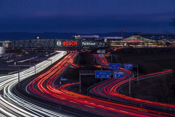 A8 motorway at Stuttgart Airport with Bosch multi-storey car park in the evening, cars create light