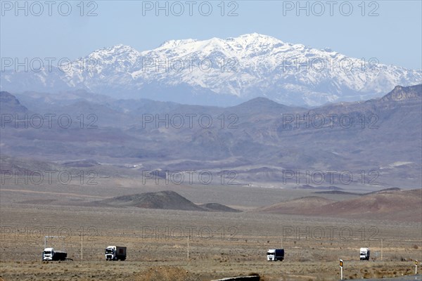 Truck on a motorway in the central desert of Iran, snow-capped mountains can be seen in the
