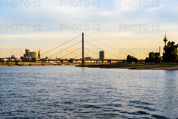 View of a city with a suspension bridge over a river at dusk, Theodor-Heuss-Bruecke, Duesseldorf,