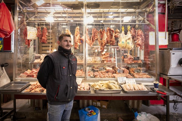 Butcher, meat trader posing proudly in front of his market stall, display of fresh meat, butchery,