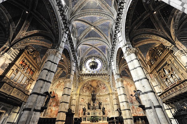 The nave of the cathedral with its black and white striped marble columns, cross and round arches,