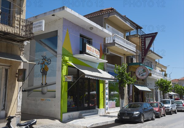 Modern building with a colourful facade and parked vehicles on the roadside, commercial street,
