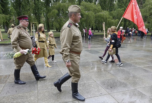 Men in Russian uniforms walk to the Russian memorial in Treptower Park in Berlin on the 74th
