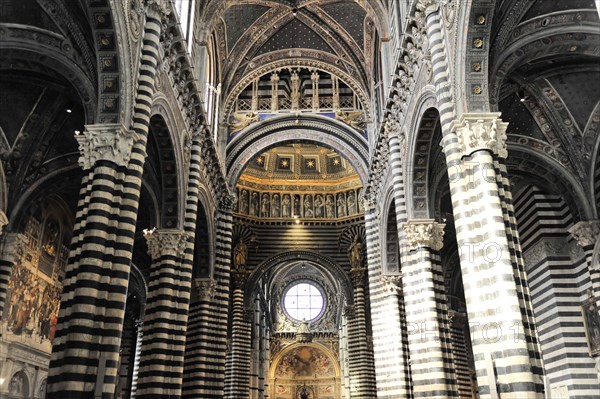 The nave of the cathedral with its black and white striped marble columns, cross and round arches,