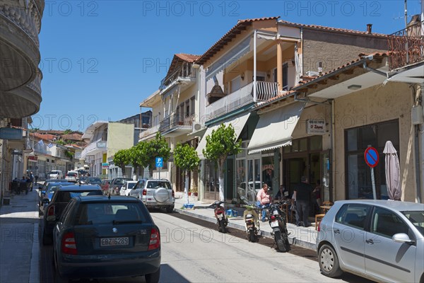 Urban street with shops, car parks and pedestrians on a sunny day, commercial street, Soufli,