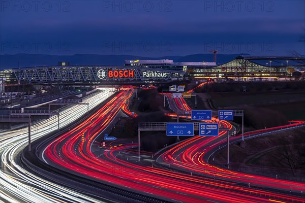 A8 motorway at Stuttgart Airport with Bosch multi-storey car park in the evening, cars create light