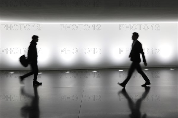 Members of the German Bundestag walk through a tunnel. The tunnel connects the Reichstag and the