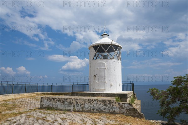 White lighthouse at the edge of a coast with cloudy sky in the background, old town, Kavala, Dimos