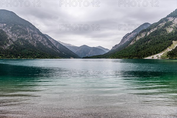 A peaceful lake surrounded by mountains under a cloudy sky, Plansee, Heiterwang, Tyrol, Austria,