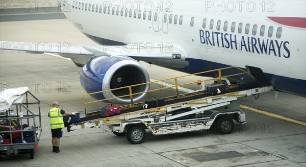 Baggage handler loading luggage onto British Airways plane at gatwick airport, London, England,
