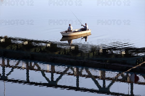 Anglers cast their rods from a boat under a bridge reflected in the Oder, Mescherin, 13 October