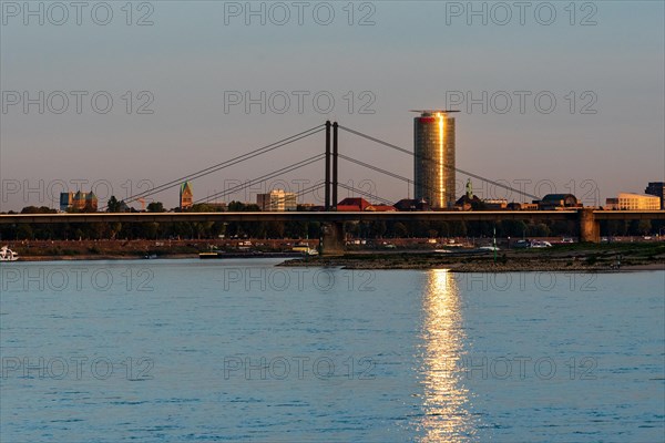 A river with a bridge and an illuminated skyscraper in the background at sunset,