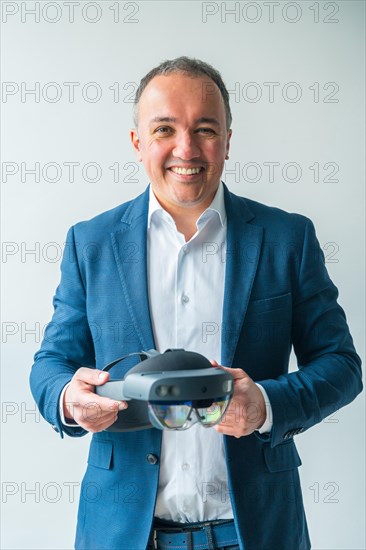 Vertical studio portrait with grey background of a confident businessman holding a futuristic mixed