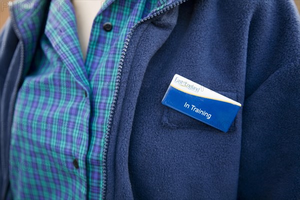 Model released teenage girl in uniform for her job in a Co-operative shop, UK wearing a badge