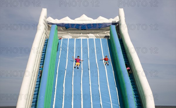 Children playing on giant inflated slide seaside attraction, Great Yarmouth, Norfolk, England,