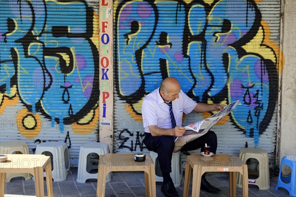 Reading newspaper, bazaar district, Eminoenue, Istanbul, European part, Istanbul province, Turkey,