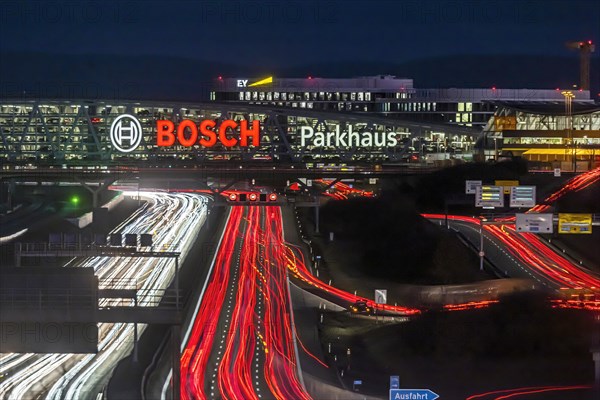 A8 motorway at Stuttgart Airport with Bosch multi-storey car park in the evening, cars create light