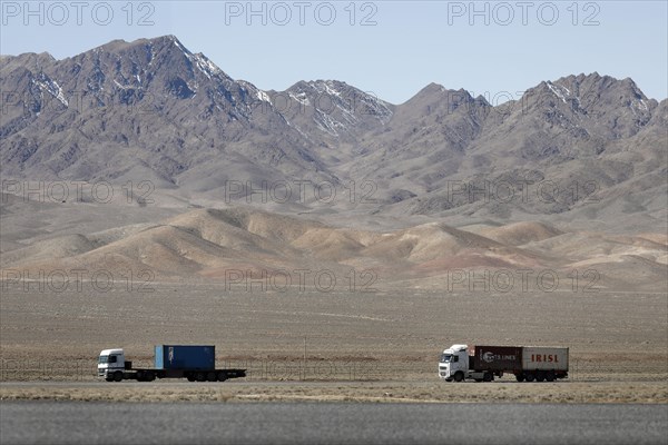 Truck on a motorway in the central desert of Iran, snow-capped mountains can be seen in the