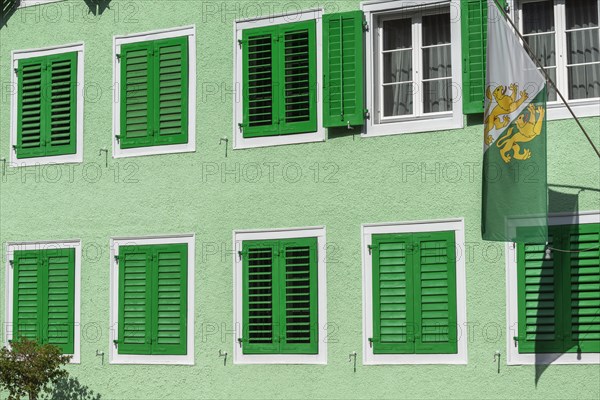 Old town of Dissenhofen on the Rhine, green house, shutters, flag with cantonal coat of arms,