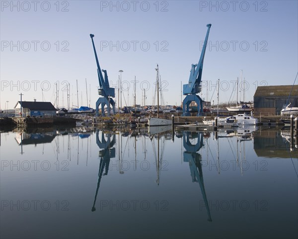 Two large blue industrial cranes reflected in water of Wet Dock marina, Ipswich, Suffolk, England,