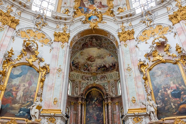 Interior view of a baroque church with richly decorated golden ornaments and ceiling frescoes,