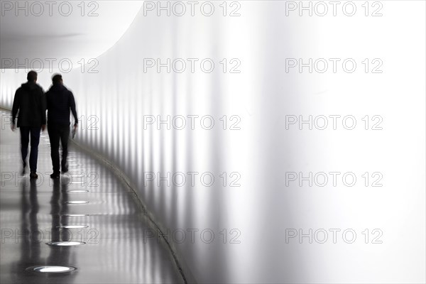 Members of the German Bundestag walk through a tunnel. The tunnel connects the Reichstag and the