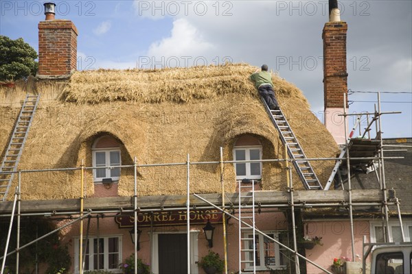 A thatcher completing the re-thatching of a traditional country pub, the Sorrel Horse, Shottisham,