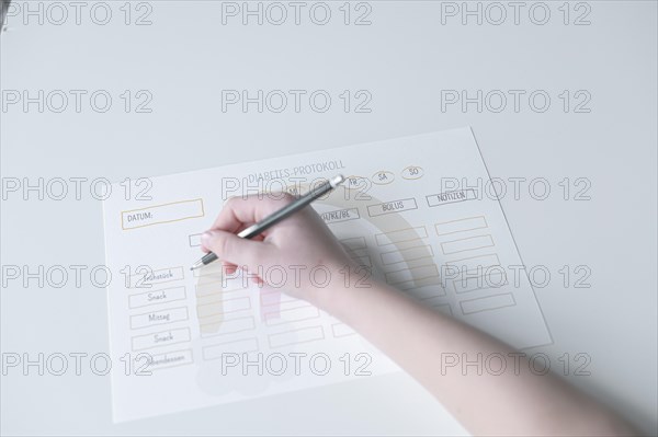 Diabetes log, daily log of food and insulin administration, food log, hand of a child holding a pen