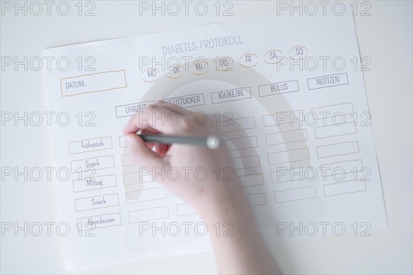Diabetes log, daily log of food and insulin administration, food log, hand of a child holding a pen