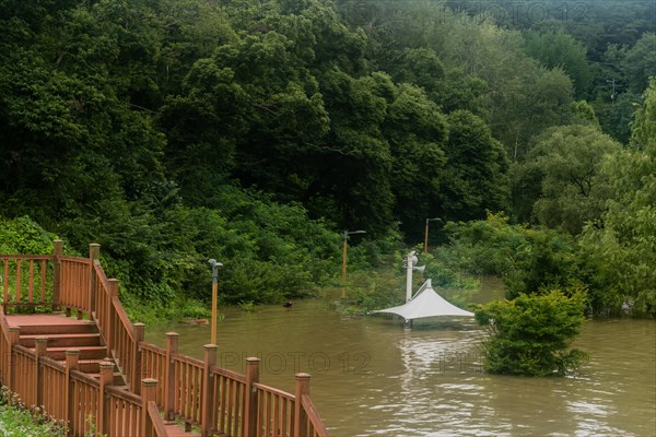 White awning over flooded river where picnic table has been submerged under water from monsoon
