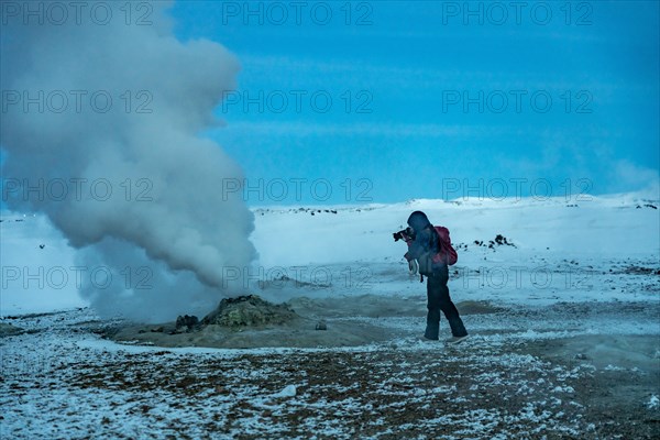 Adventurous photographer woman in winter in Iceland photographing in the Hverir or Namafjall