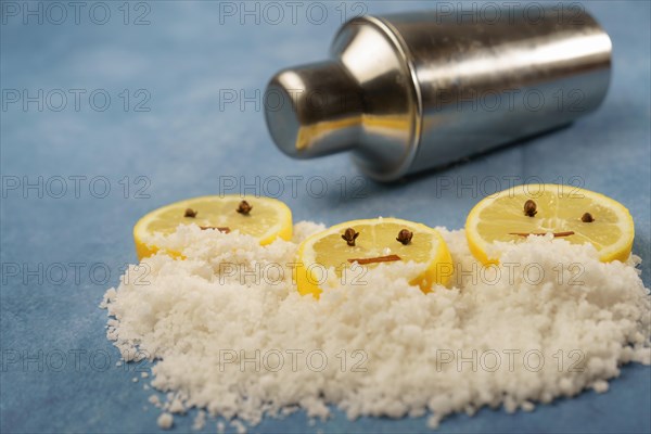 Lemon slices with cloves and cinnamon forming a smiley face on a pile of salt next to a shaker with